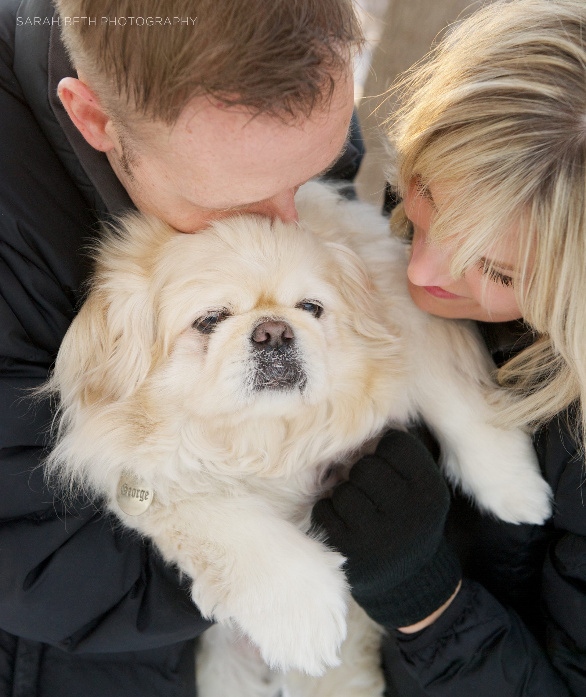 man and woman kissing pekinese dog